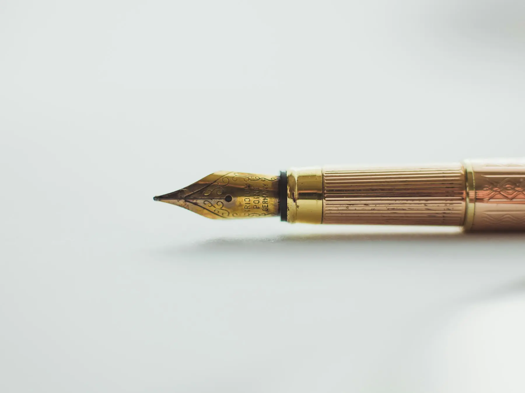 A gold fountain pen resting on a white desk