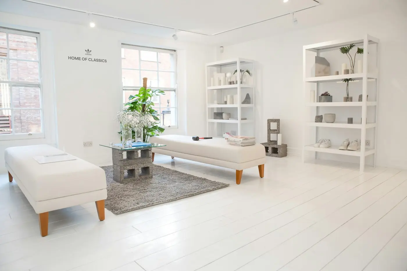 A bright white consultation room with treatment beds and open shelving