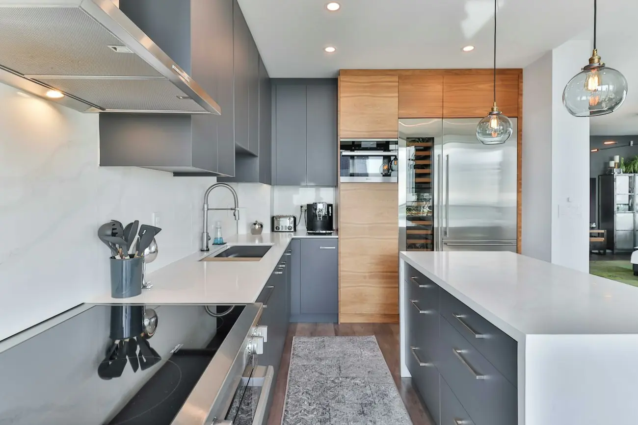 A kitchen with graphite cabinets, a marble backsplash and a walnut pantry wall