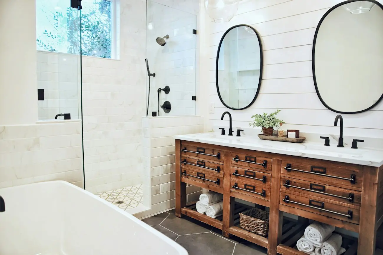 A bathroom with a reclaimed wood vanity, oval mirrors and shiplap walls