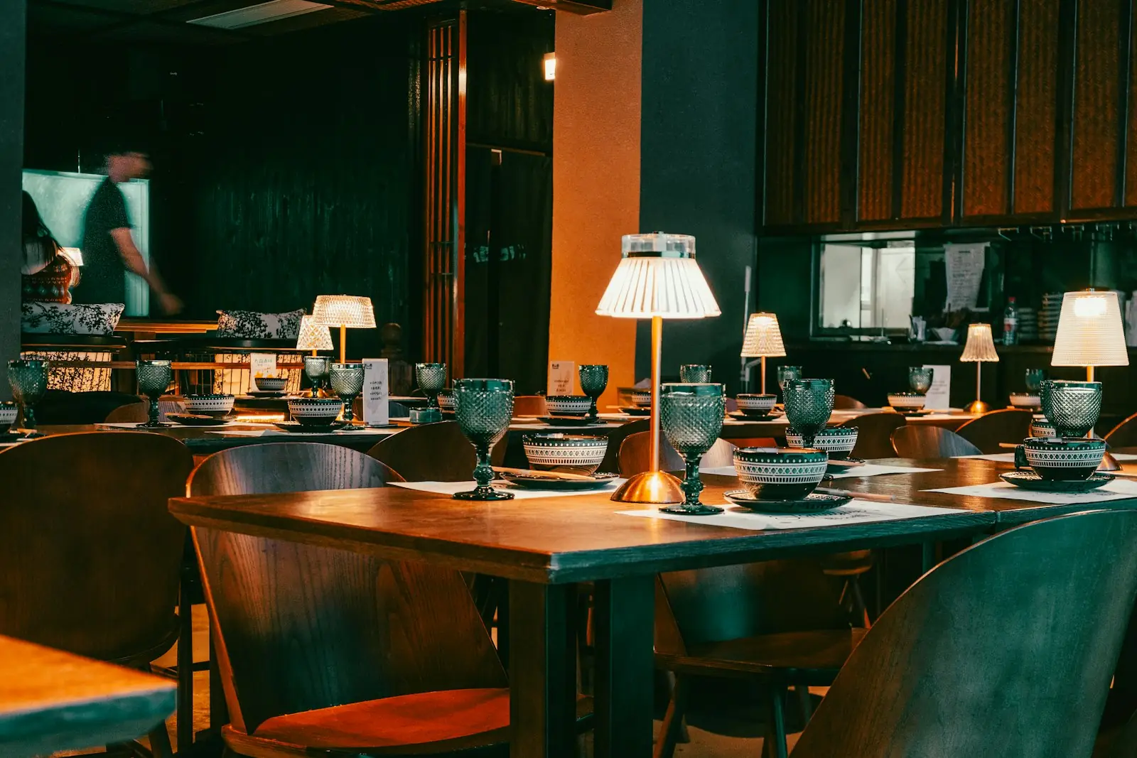 The dining room at Lucciola with green banquettes and small table lamps
